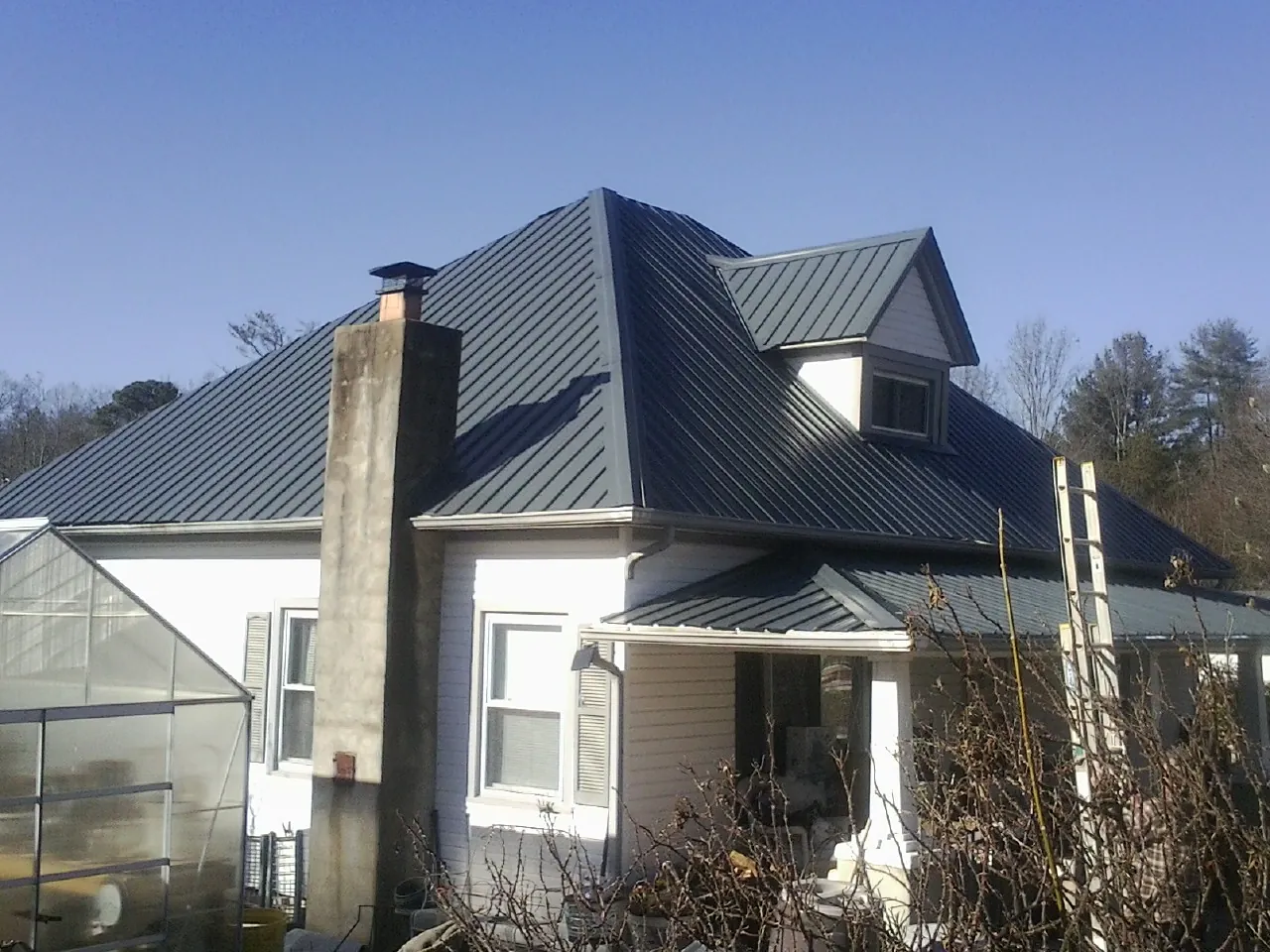 Dark blue standing seam metal roof on a white farmhouse with dormer — Slate & Tile Roof Repair by Roofing Brothers in Fort Hill