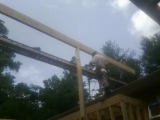 Carpenter setting a ridge beam over a new addition frame — Ice Dam Removal by Roofing Brothers in Fort Hill