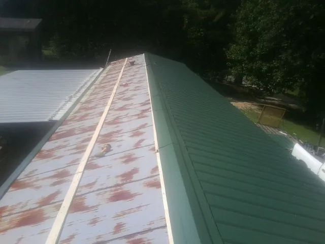 Old rusted panels beside newly installed green metal roofing — Wind Damage Roof Repair by Roofing Brothers in Fort Hill