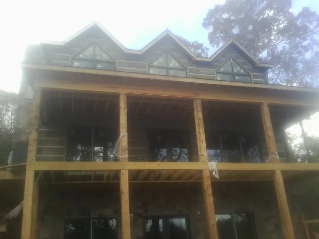 Dormers and porch framing on a large log home under construction — Roof Coating work by our crew in Fort Hill
