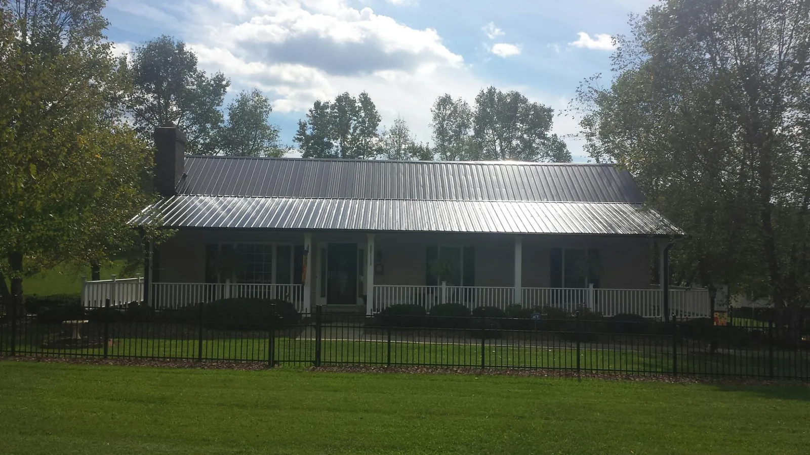 Gray metal roof on a brick ranch with a full width front porch — Gutter Guard Installation work by our crew in Fort Hill