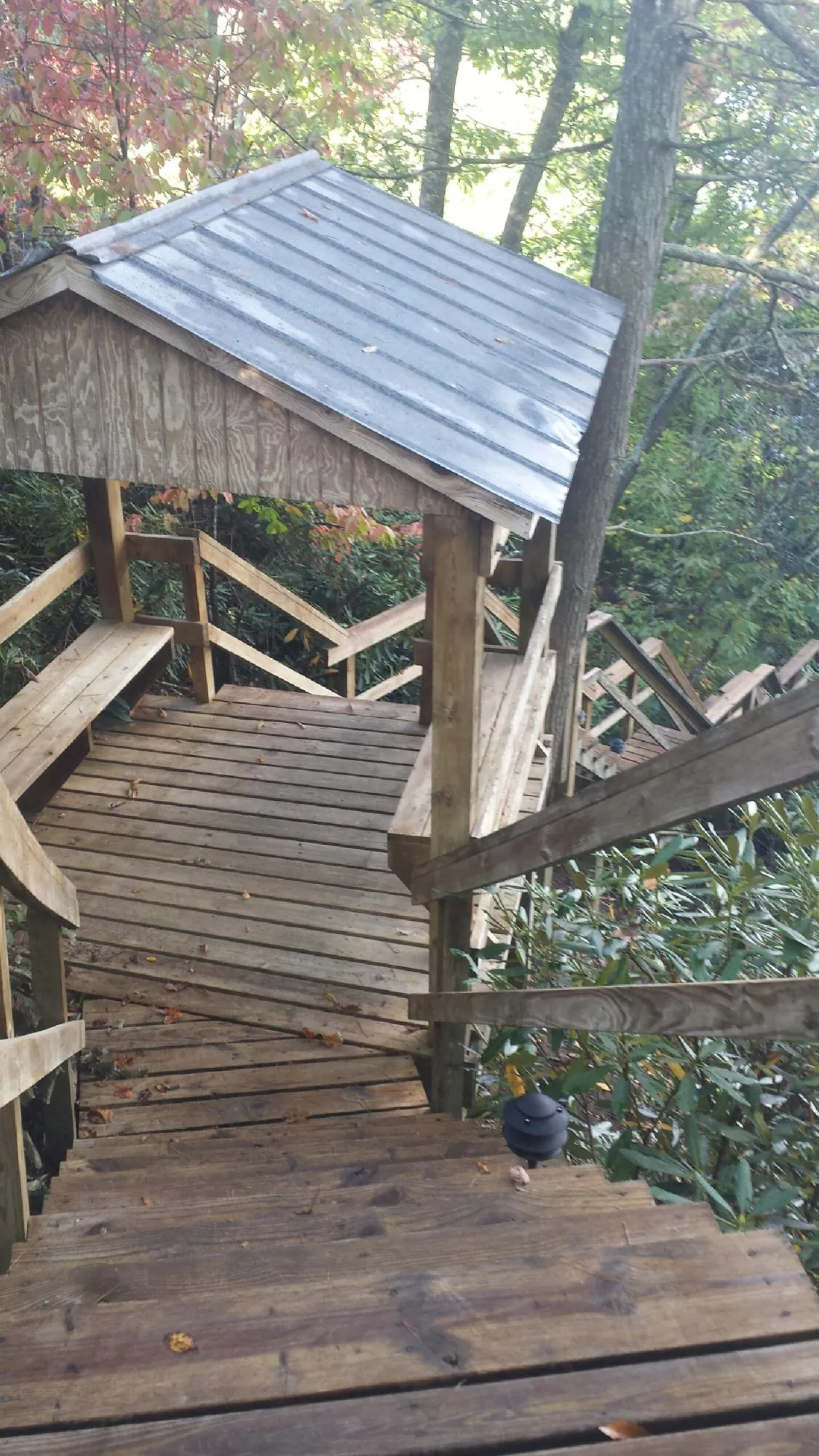 Metal roofed shelter over wooden steps on a wooded walkway — Skylight Repair & Installation work by our crew in Fort Hill
