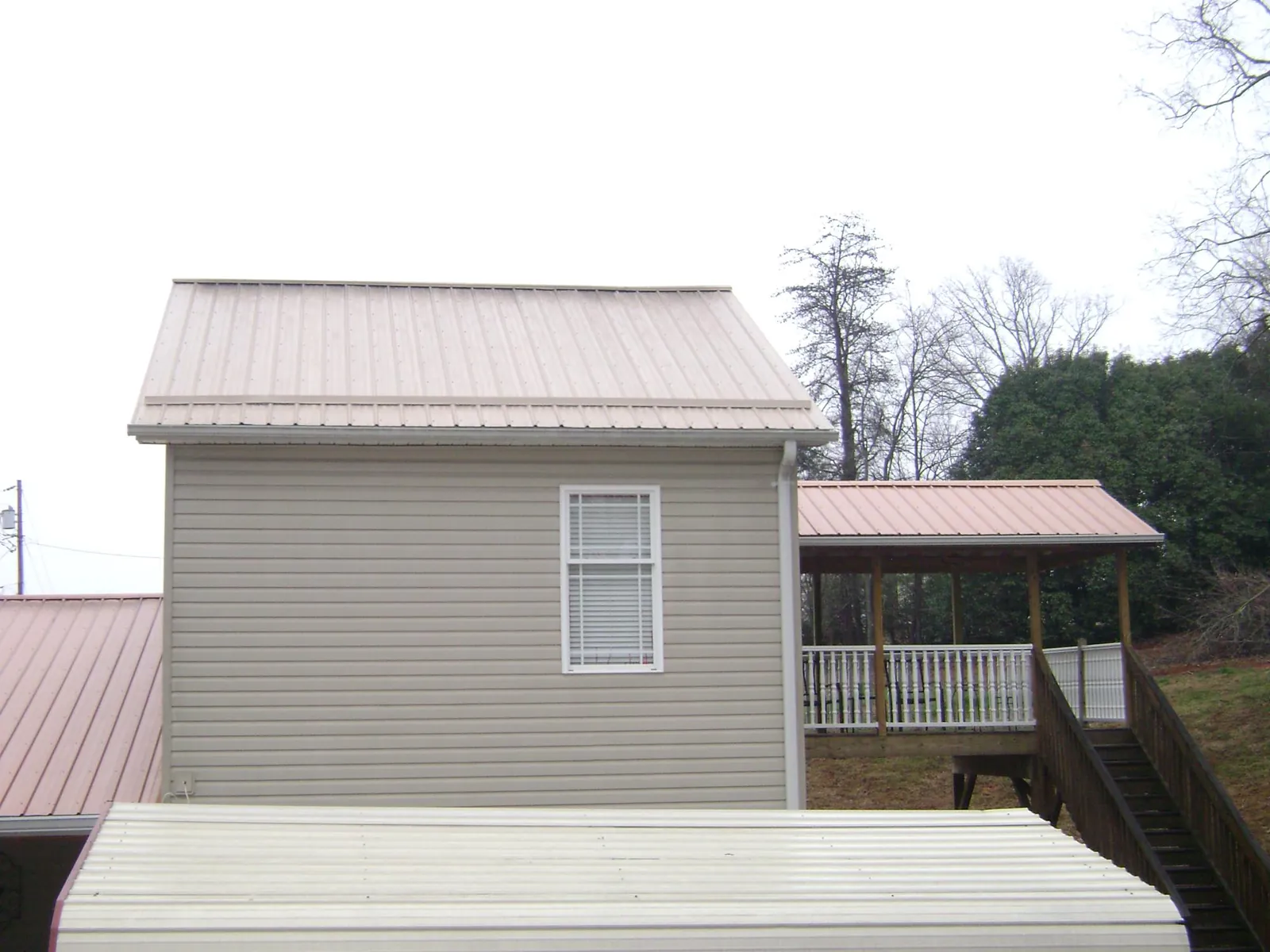 Tan metal roofs on a two story addition and attached porch, from a Roof Replacement job in Fort Hill