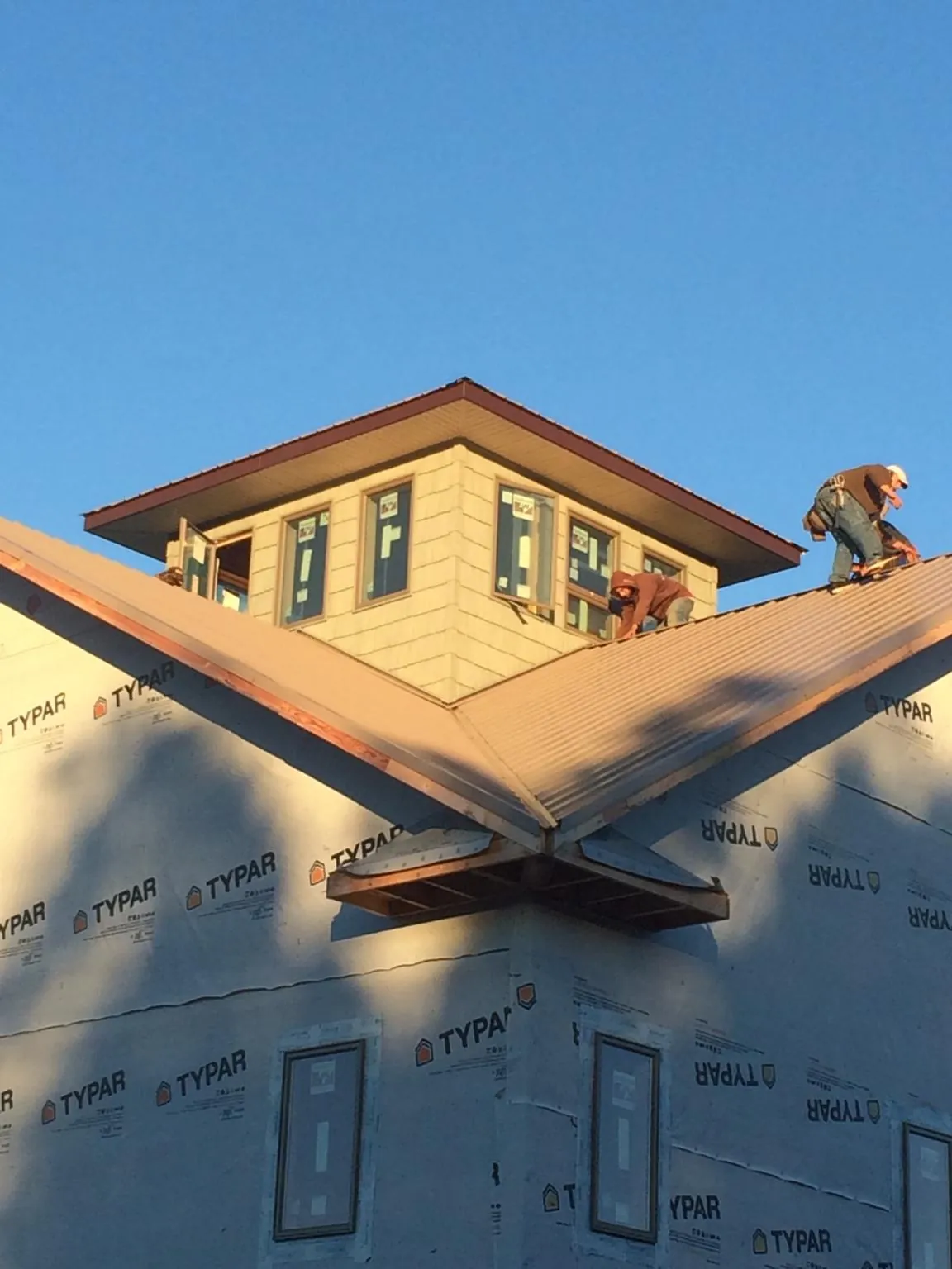 Roofers working around a rooftop cupola on a new metal roof at sunset — Roof Waterproofing in Fort Hill by Roofing Brothers